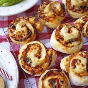 Rotolini di Pizza {Ricetta Facile!} 3 Girelle di Pizza appena sfornate su una griglia su un tavolo.