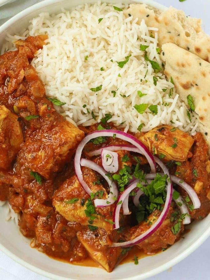 Curry di Pollo Facile {Rapido e Sano} 3 Una ciotola piena di curry di pollo gustoso e salutare, riso bianco e un po' di pane naan.