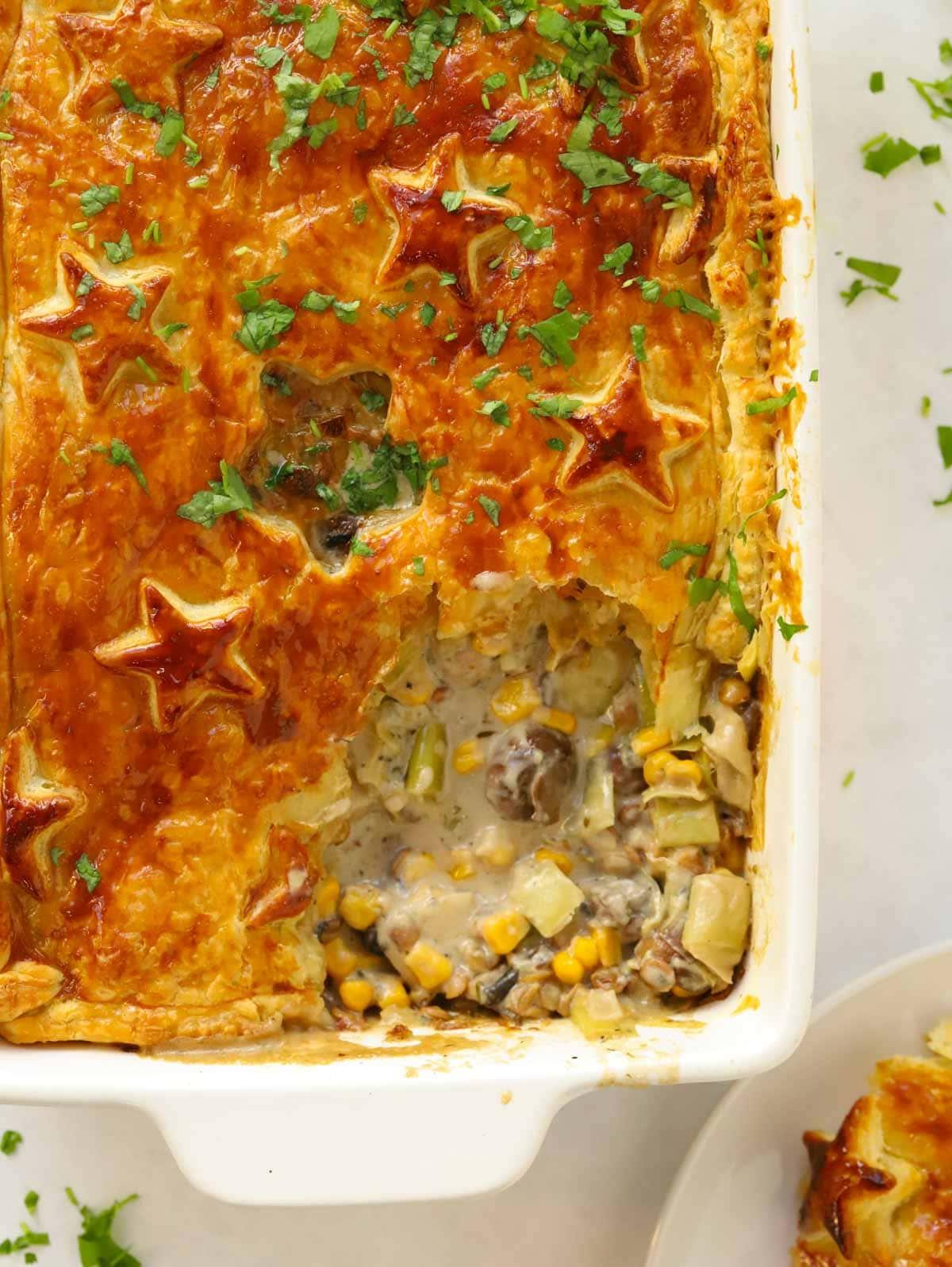 Torta Salata Vegetariana al Formaggio {con Pasta Sfoglia} 3 Torta salata vegetariana con crosta di pasta sfoglia dorata appena sfornata, con un angolo mancante che rivela il delizioso ripieno di verdure.