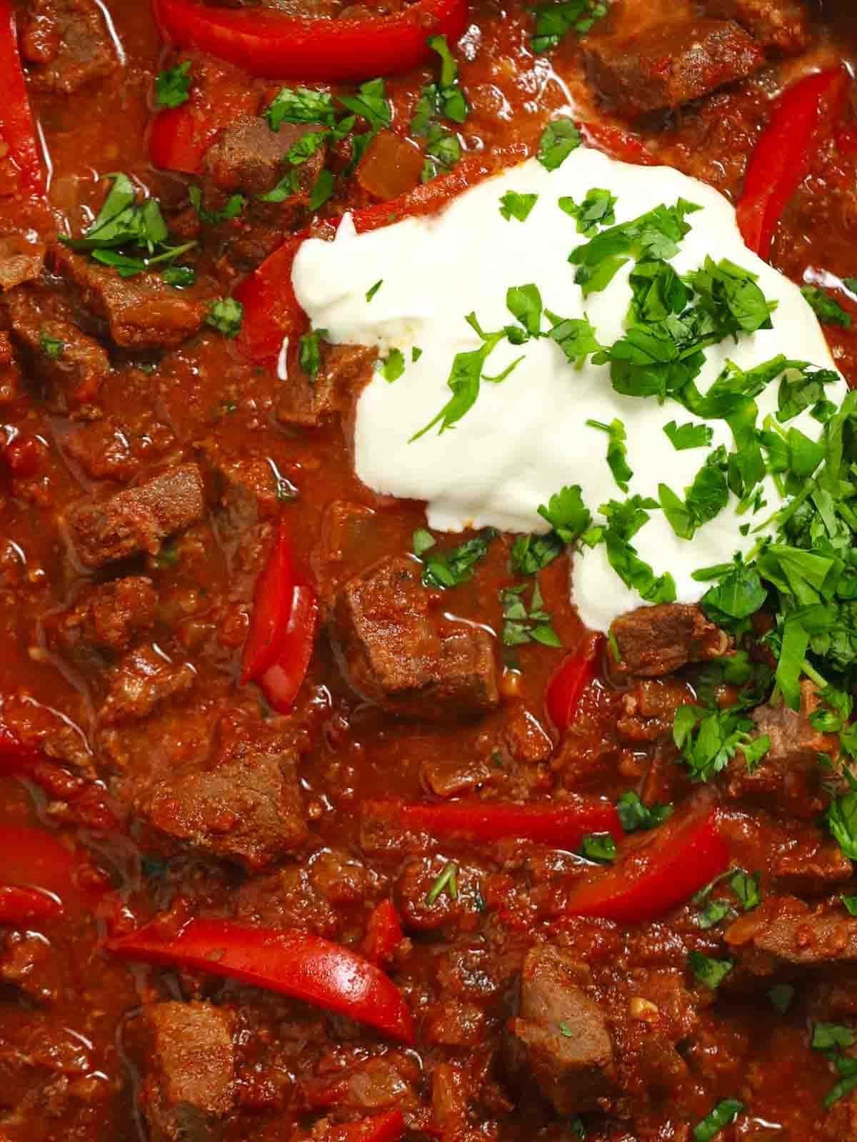 Gulasch di Manzo 3 Un primo piano di goulash di manzo con peperoni rossi in una salsa ricca.