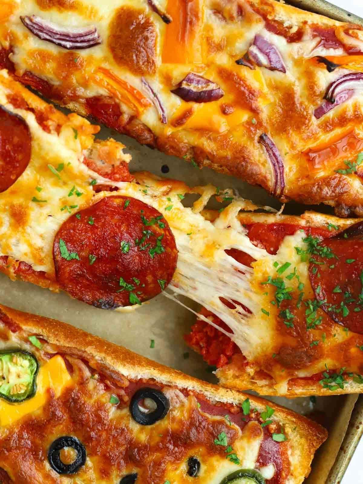 Pizza di Pane Francese 3 Una pizza di pane francese cotta che viene strappata a metà per mostrare il formaggio filante.