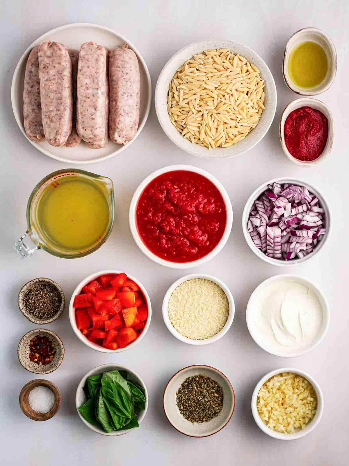 Semplice Orzo con Salsiccia {Pentola Unica} 4 Ingredienti per Orzo con Salsiccia disposti su un piano di lavoro in piccole ciotole.