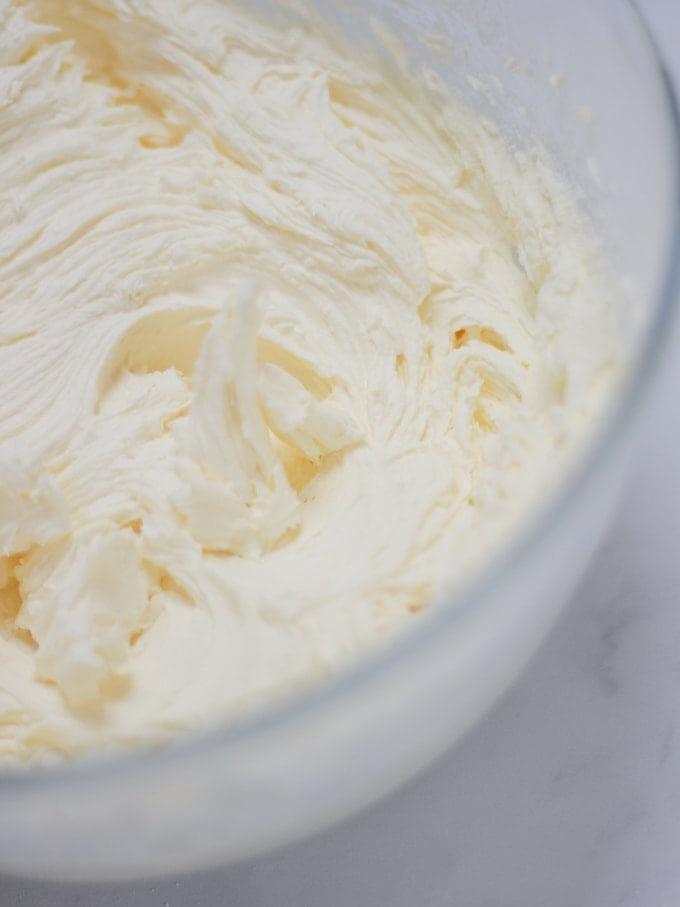 La Ricetta Definitiva della Torta al Pimms 4 Ciotola di crema al burro per Pimms Cake su sfondo bianco.