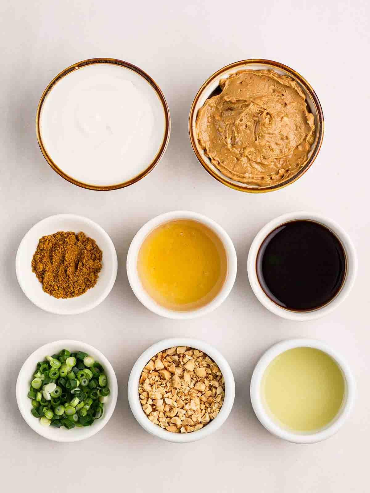Salsa Satay (Ricetta Facile!) 4 Gli ingredienti per preparare la Salsa Satay fatta in casa disposti in piccole ciotole su un piano di lavoro bianco.
