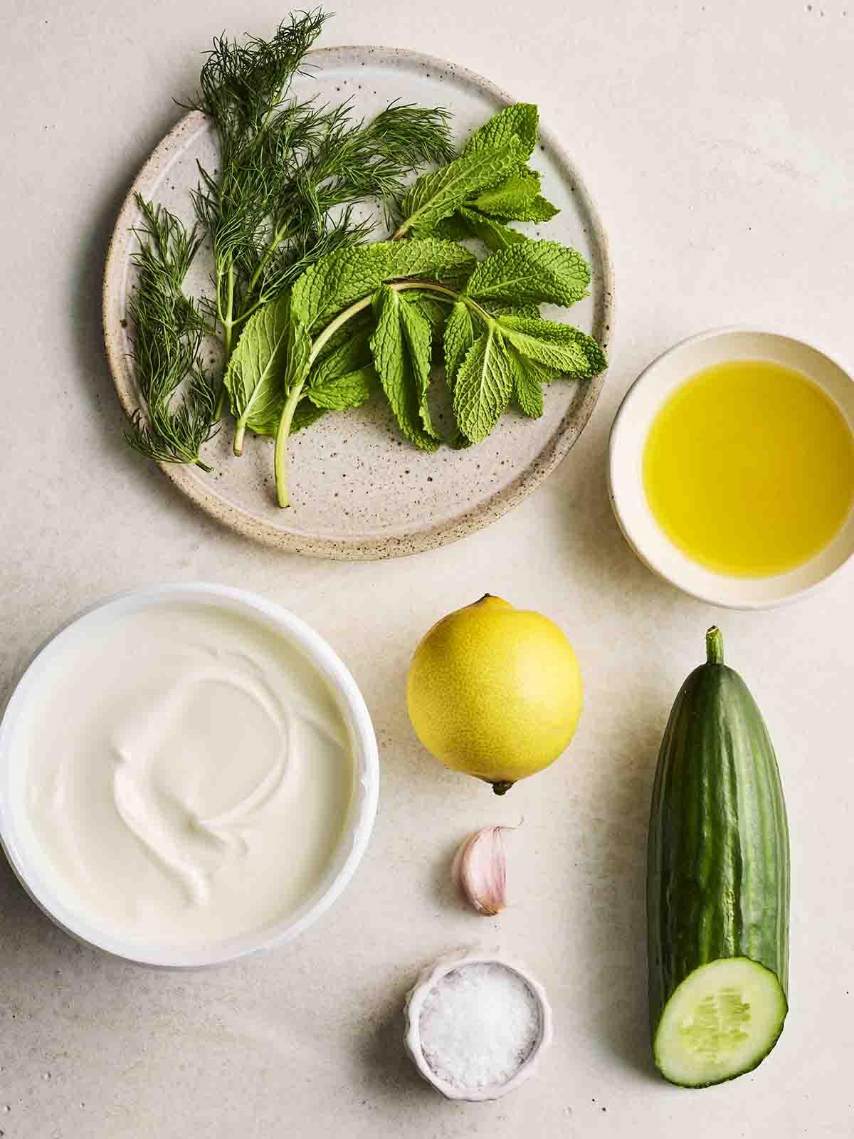 Tzatziki {Ricetta Facile!} 4 Gli ingredienti per preparare il Tzatziki disposti in ciotole su un bancone.