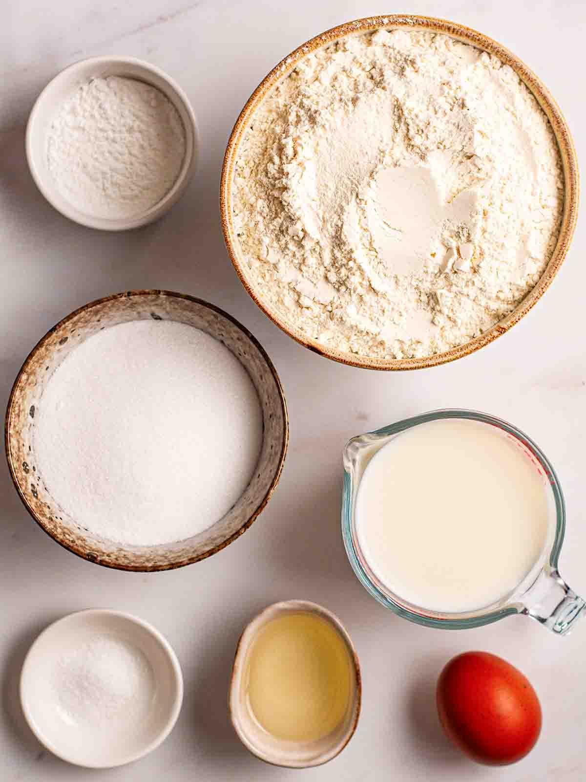 Pancakes Americani {Ricetta Facile!} 4 Gli ingredienti per i Pancakes Americani disposti su un piano di lavoro. Una vista dall'alto, con gli ingredienti in ciotole separate.