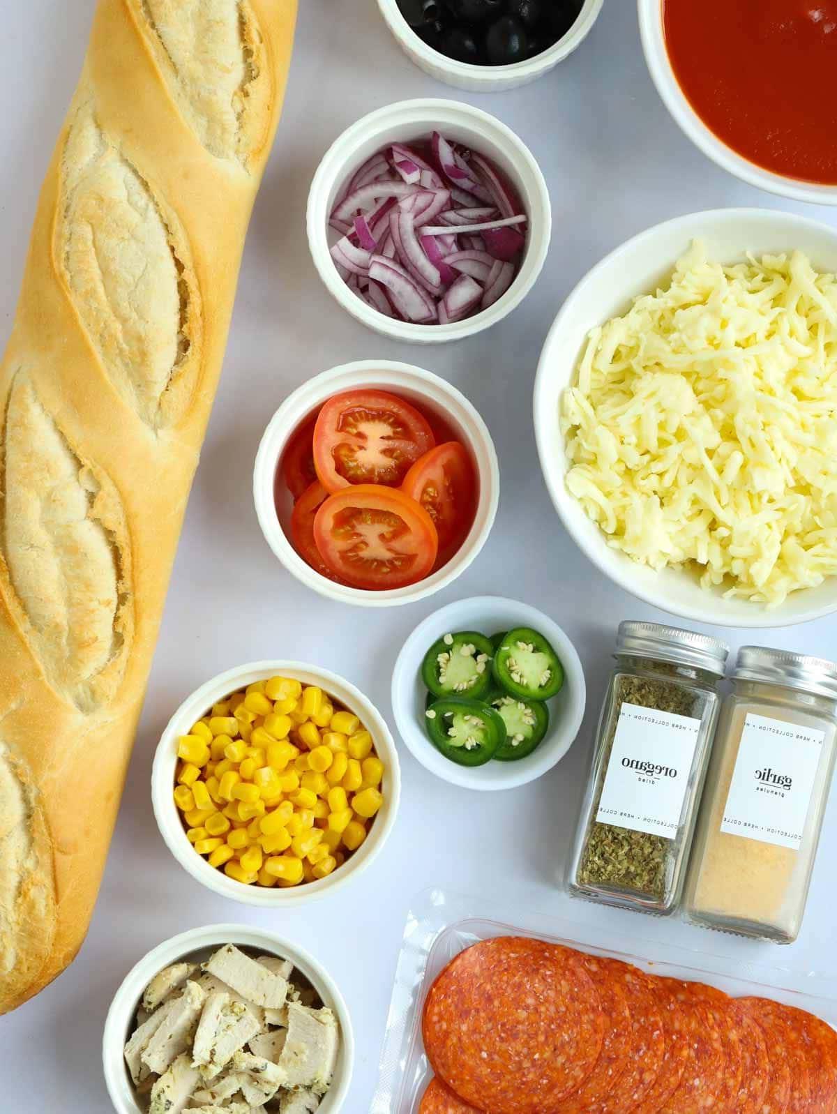 Pizza di Pane Francese 4 Gli ingredienti per una Pizza di Pane Francese disposti su un bancone. Baguette, formaggio, erbe aromatiche e una selezione di condimenti.