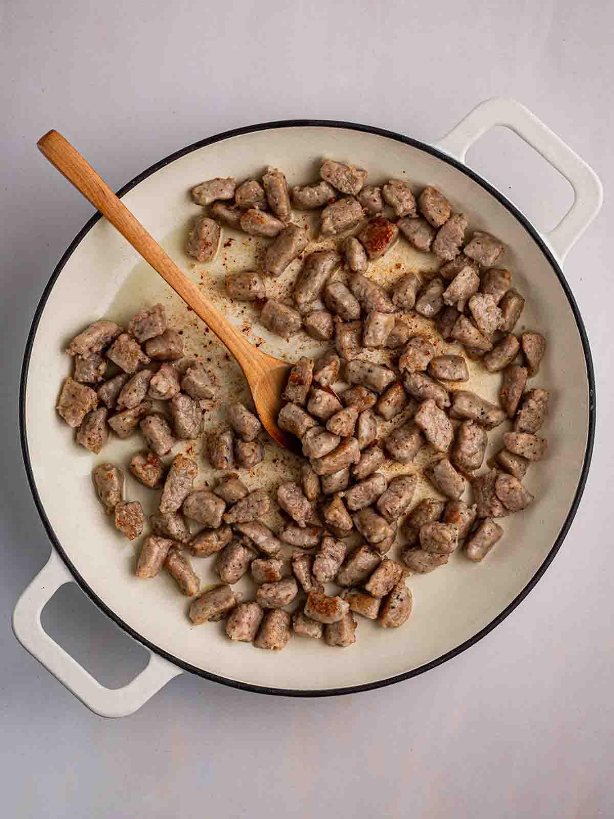 Semplice Orzo con Salsiccia {Pentola Unica} 5 Una pentola piena di pezzi di salsiccia, che si stanno dorando nell'olio, per il passaggio 1 della ricetta dell'Orzo con Salsiccia.