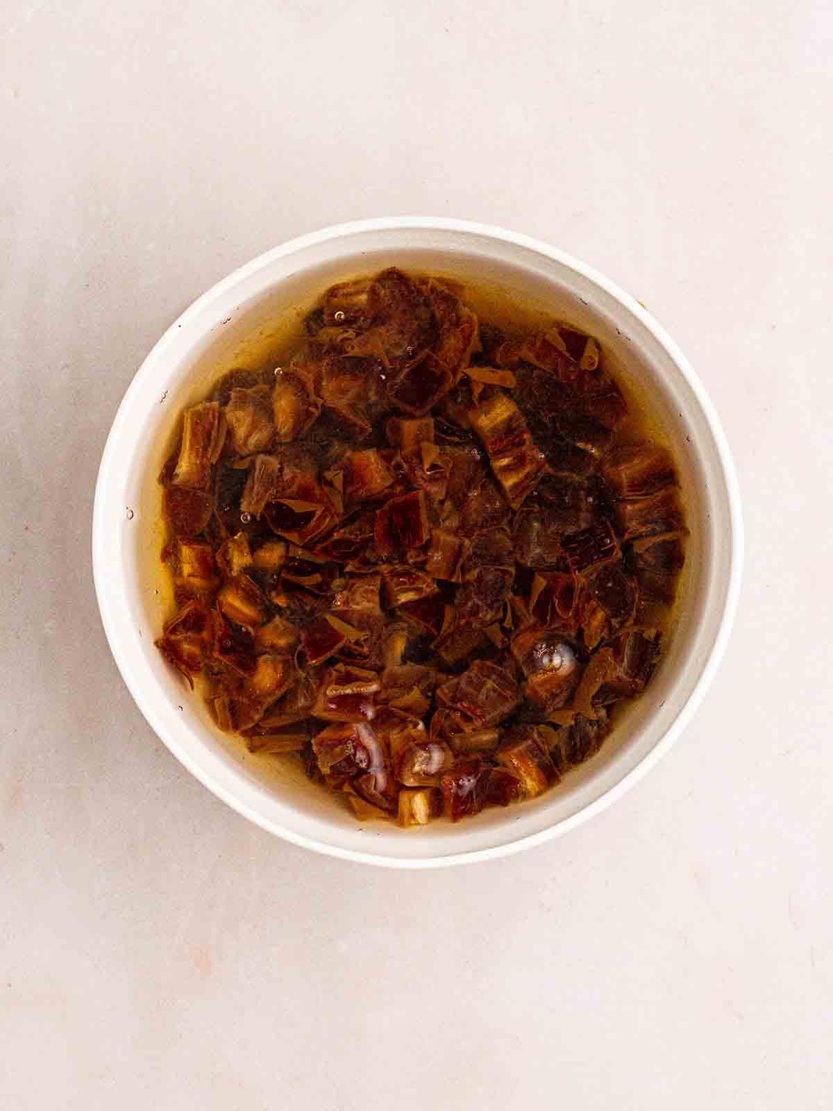 Pudding al Caramello Appiccicoso in Slow Cooker 5 Datteri tritati in ammollo in una ciotola per il passaggio 1 della preparazione del Budino al Toffee Appiccicoso al Slow Cooker.