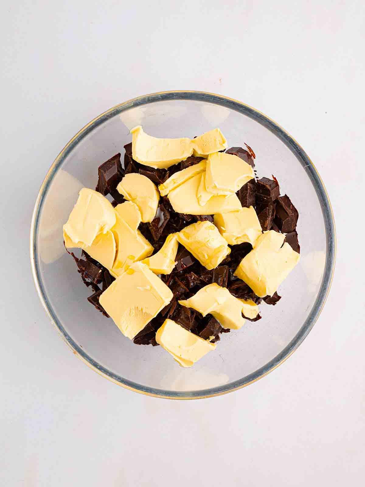 Rocky Road {La Migliore Ricetta di Sempre!} 5 Burro e pezzi di cioccolato in una ciotola di vetro per il passaggio 1 del metodo per la ricetta Rocky Road.