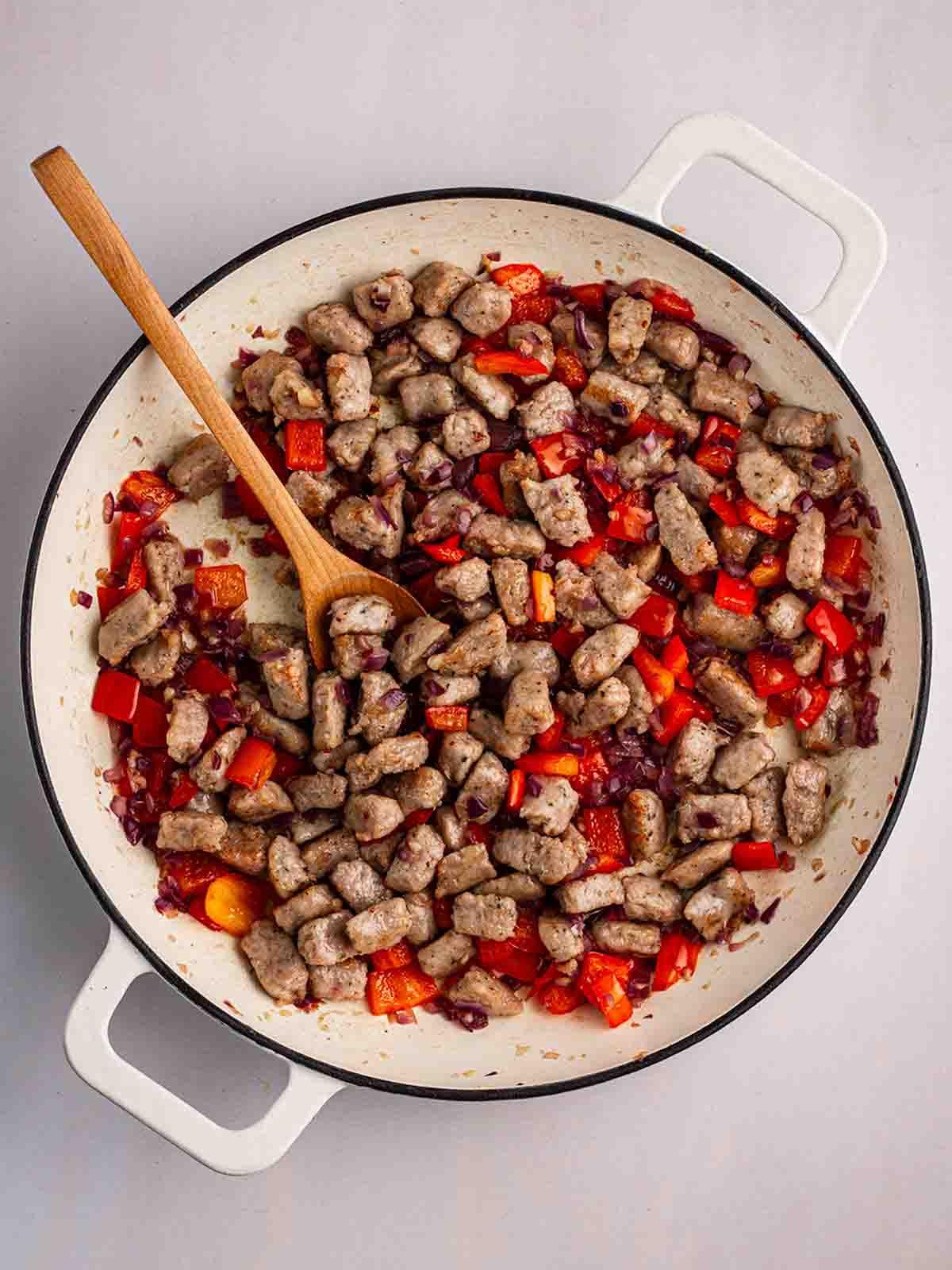 Semplice Orzo con Salsiccia {Pentola Unica} 6 Pezzi di salsiccia cotta con peperone rosso che cuociono in una pentola per per il passaggio 2 della ricetta dell'Orzo con Salsiccia.