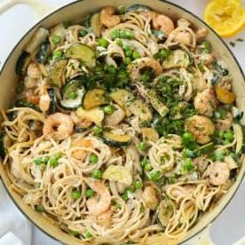 Piano Pasti Settimanale 2 7 Una grande ciotola piena di pasta ai gamberi con zucchine, piselli, gamberi e spaghetti, pronta da mangiare.