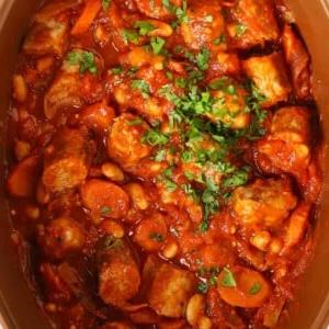 Stufato di Salsicce a Cottura Lenta {Ricetta Facile} 7 A close up image of a slow cooker sausage casserole, with chopped sausages, carrots and beans in a tomato sauce.