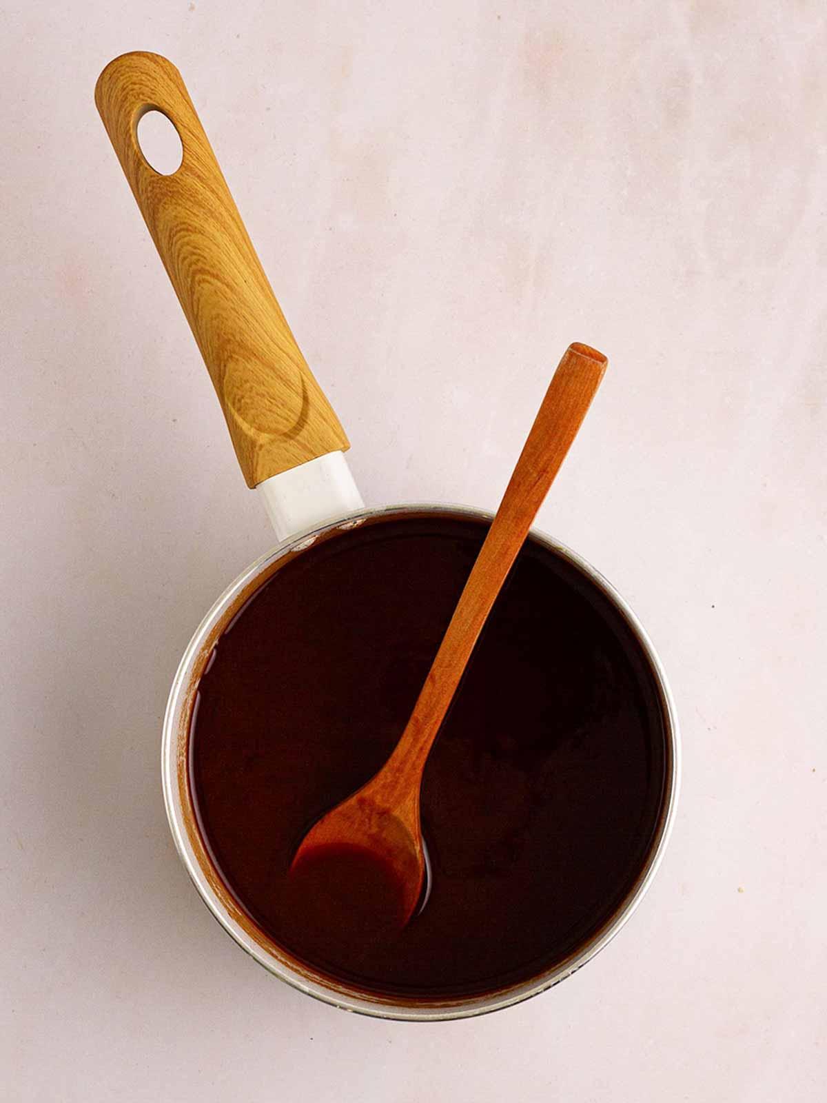Anatra alla pechinese in pentola a cottura lenta 8 Una padella con salsa pechinese con un cucchiaio di legno per il passaggio 4 della ricetta dell'Anatra alla Pechinese in Slow Cooker.