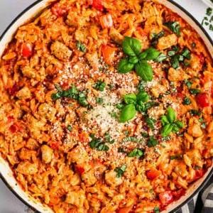 Semplice Orzo con Salsiccia {Pentola Unica} 9 Uno sguardo ravvicinato al piatto di orzo con salsiccia in una pentola con basilico e parmigiano sopra.