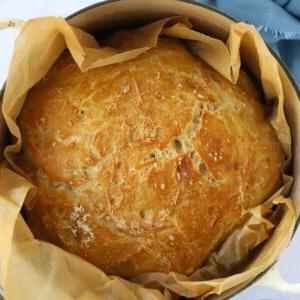 Pane Senza Impasto {La Ricetta Notturna Più Semplice di Sempre} 9 Un filone di pane croccante fatto in casa, cotto e pronto per essere servito, in una pentola con carta da forno per la ricetta del Pane Senza Impasto.