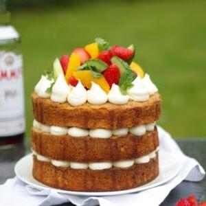 La Ricetta Definitiva della Torta al Pimms 9 Pimms cake con glassa, cetriolo, fragole, arance e menta su un piatto bianco in giardino, ricetta torta al Pimms.