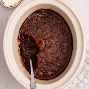 Pudding al Caramello Appiccicoso in Slow Cooker 9 Un slow cooker con Budino al Toffee Appiccicoso cotto all'interno, con una salsa sotto l'impasto. Un cucchiaio per servire.