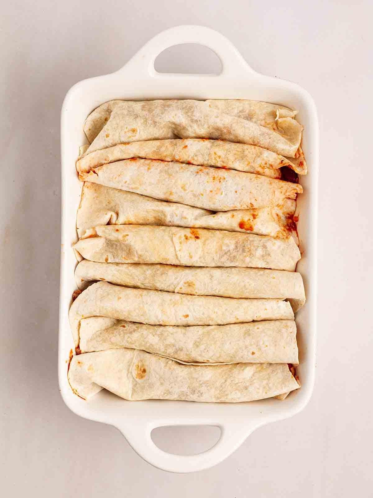 Enchiladas di Manzo 9 Una pirofila da forno con tortillas arrotolate per il passo 5 della ricetta delle Enchiladas di Manzo.