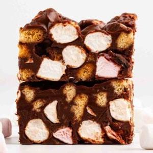 Rocky Road {La Migliore Ricetta di Sempre!} 9 Due pezzi di Rocky Road uno sopra l'altro, di lato, che mostrano un ripieno di marshmallow e biscotti all'interno del cioccolato.