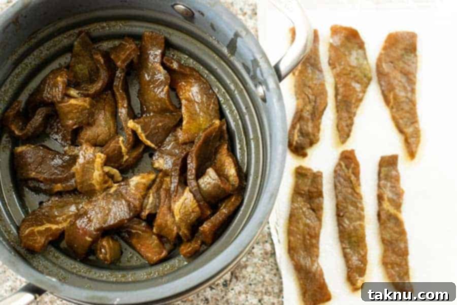 Teriyaki beef jerky in a colander and laid out on paper towels for final patting dry.