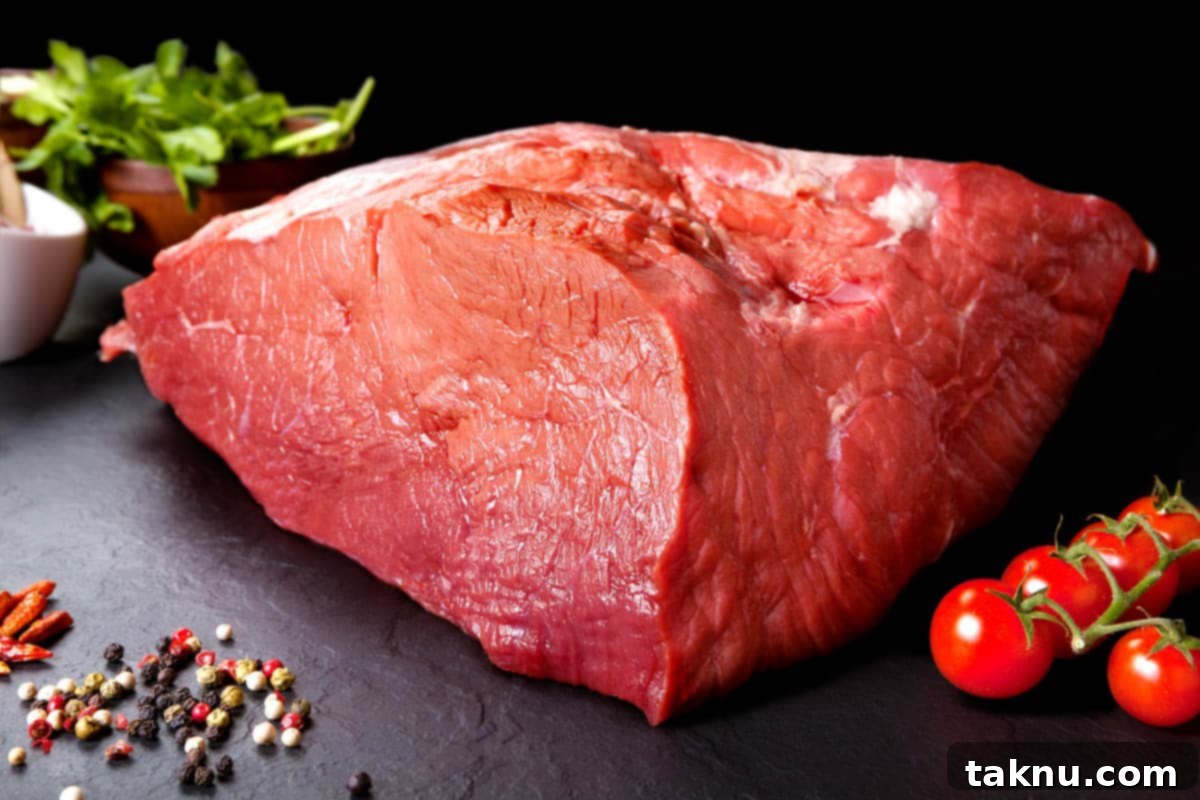 Beef Top Round on cutting board with tomatoes, showcasing the excellent texture for beef jerky