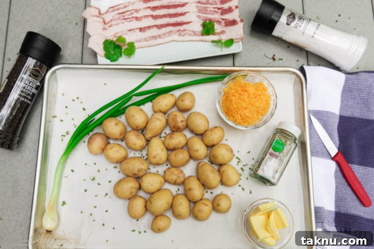 Petite gold potatoes on baking sheet with bacon, green onion, butter, and cheese surrounding the dish