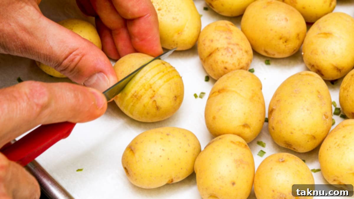 A hand demonstrating how to slice a potato, holding a sharp knife and creating thin, parallel cuts without going all the way through.