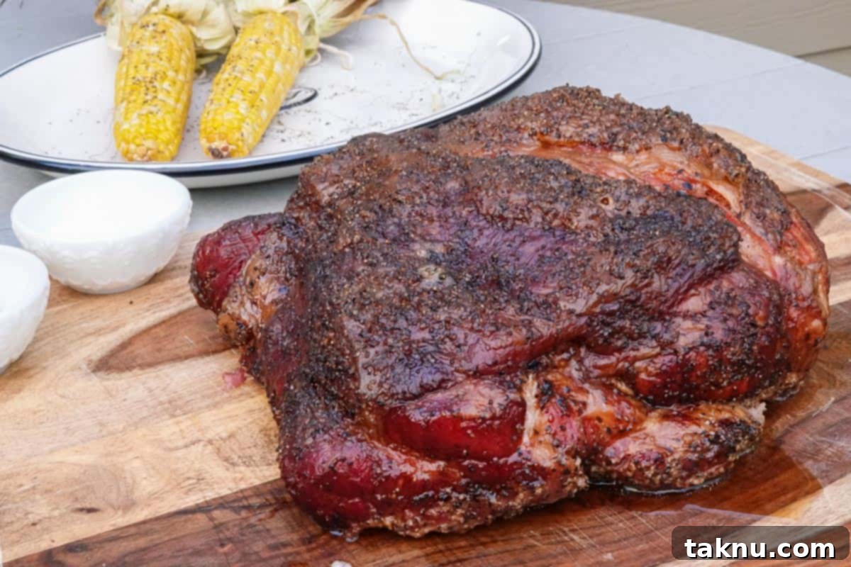 A succulent smoked pork butt resting on a rustic wooden cutting board, with kernels of corn subtly visible in the soft-focus background, highlighting the primary ingredient for these tacos.