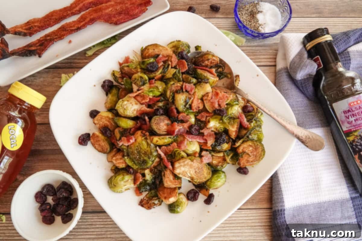 Cooked brussel sprouts on white plate topped with bacon and cranberries.