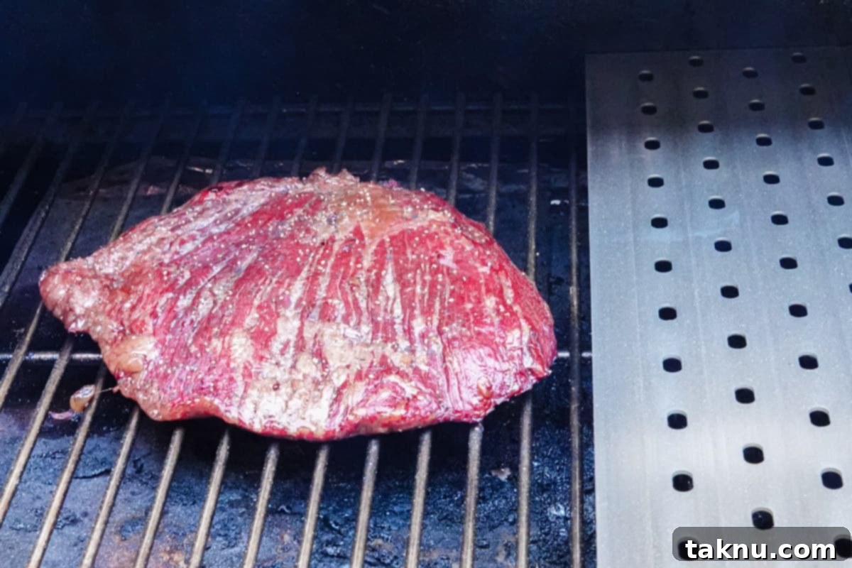 Flank steak smoking on smokers grill grate