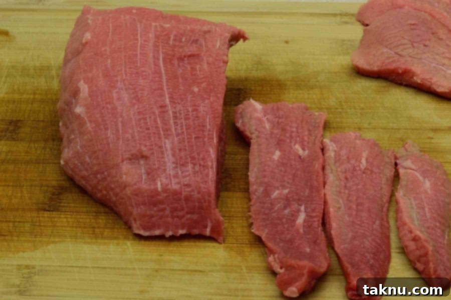 Thinly sliced Eye of Round beef strips, cut with the grain, arranged neatly for jerky preparation