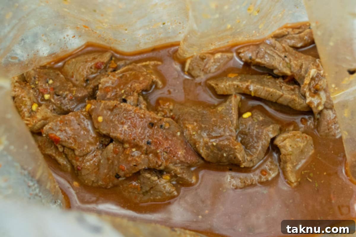 Cajun beef jerky strips marinating in a clear ziplock bag, absorbing rich flavors