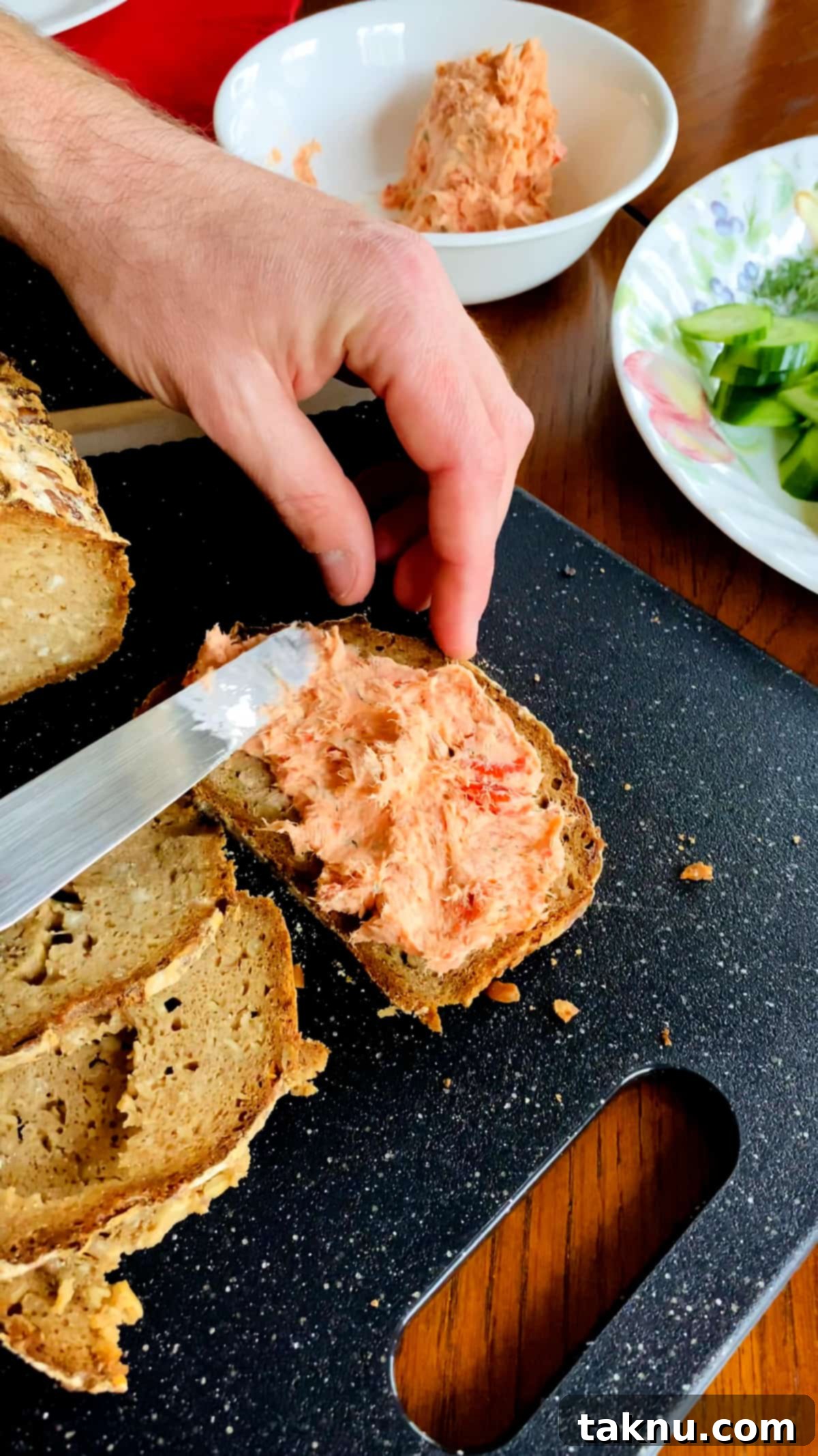 Signature Smoked Salmon Dip 2 Freshly made smoked salmon dip served on seeded bread slices with a sprinkle of dill, artfully arranged on a black cutting board, ready to be enjoyed as a gourmet appetizer.