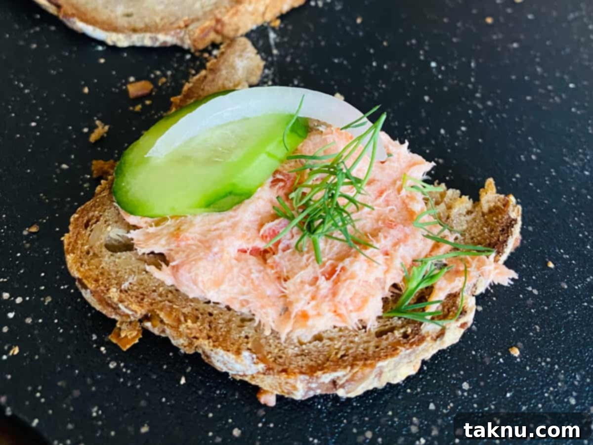 Signature Smoked Salmon Dip 8 Salmon dip on toast with cucumber and black background.
