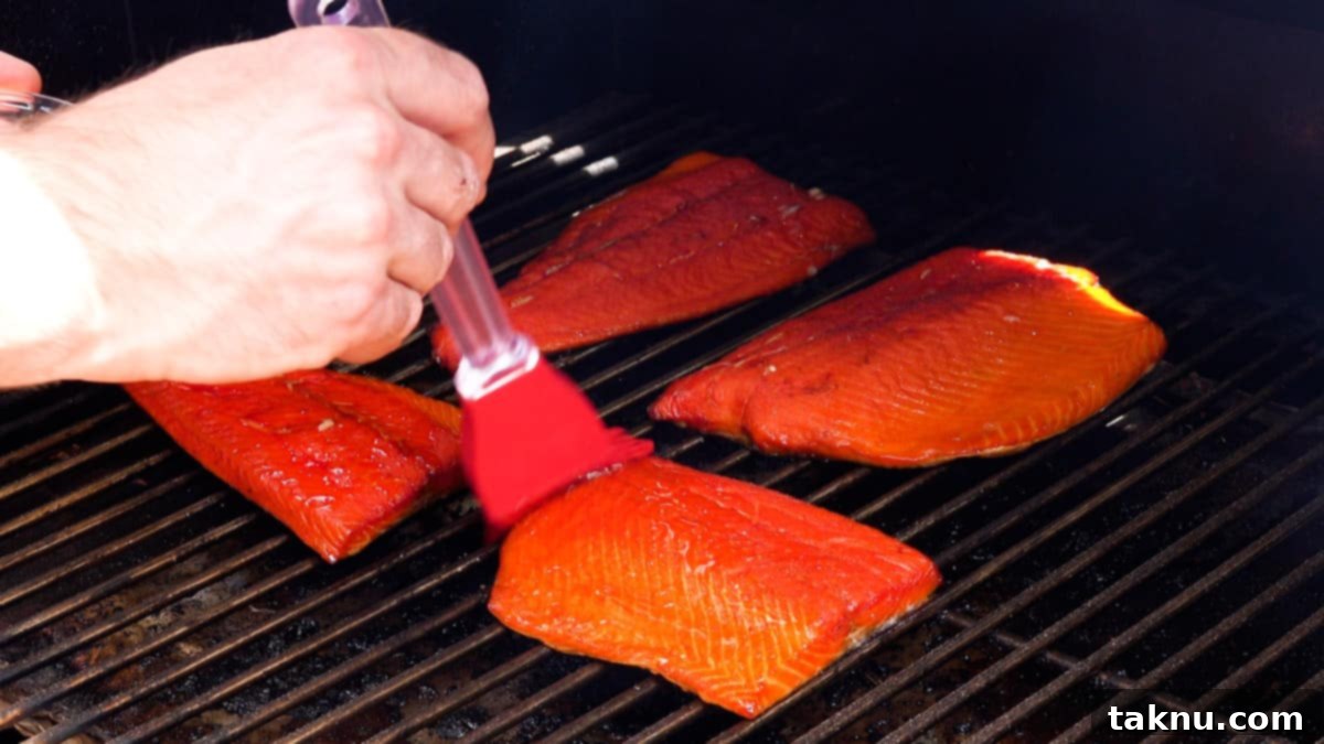 Signature Smoked Salmon Dip 3 A large salmon fillet being basted with a delicious glaze on a smoker, showing the rich color and texture achieved through the smoking process.