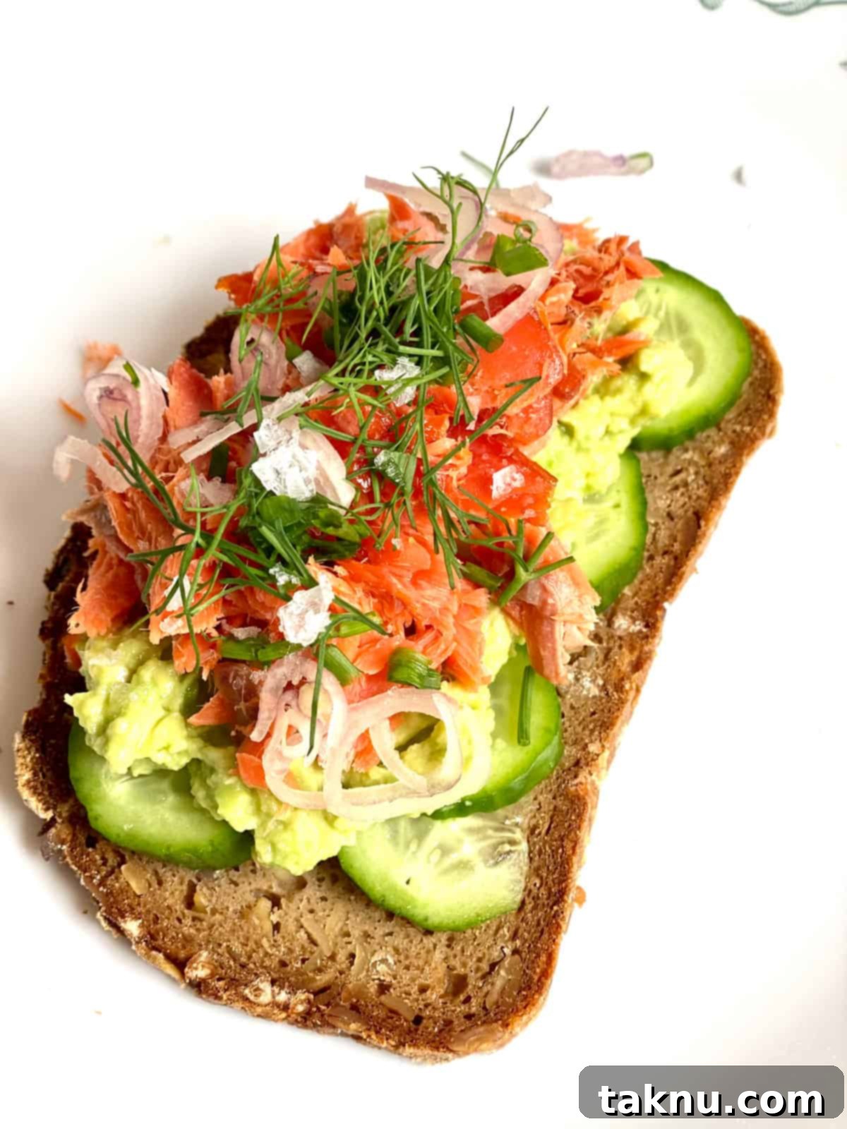 flaked salmon toast with mashed avocado, sliced cucumbers, dill, green onions, and shallots