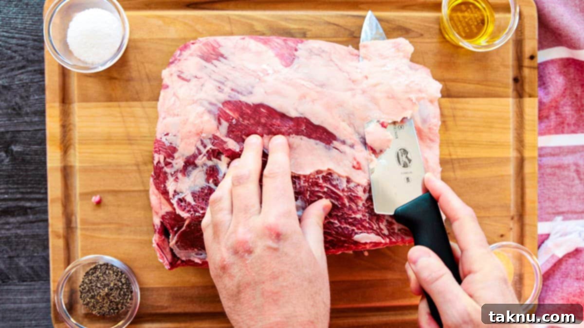 Giant Smoked Beef Ribs 3 Trimming beef ribs of fat with sharp knife on wood cutting board.