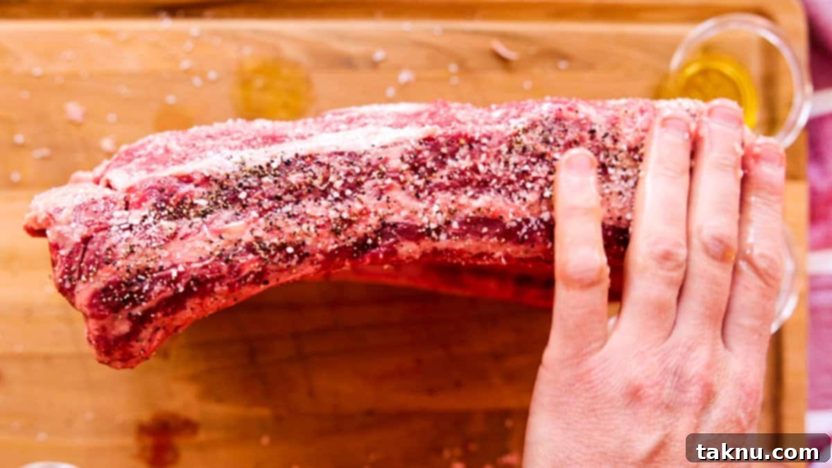 Giant Smoked Beef Ribs 4 Seasoning the side of beef ribs with salt, pepper, garlic.