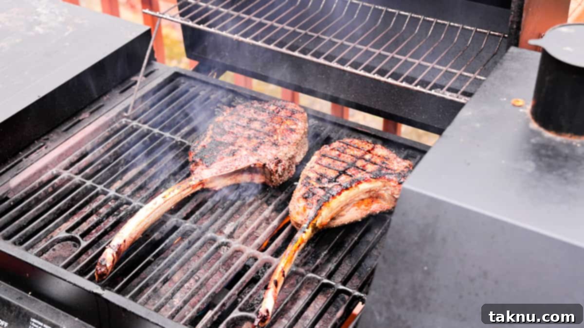 Tomahawk Steak Perfection 8 Two large Tomahawk ribeye steaks sizzling on a hot grill, emitting a delicious smoke as they cook.