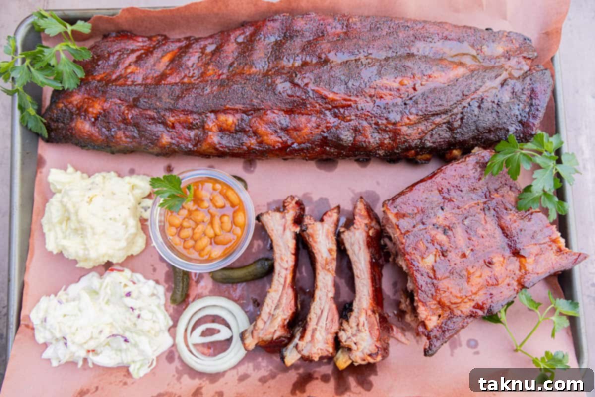 A platter featuring a full rack of sliced ribs and individual ribs, served with classic barbecue sides like coleslaw, potato salad, baked beans, and sliced onions.
