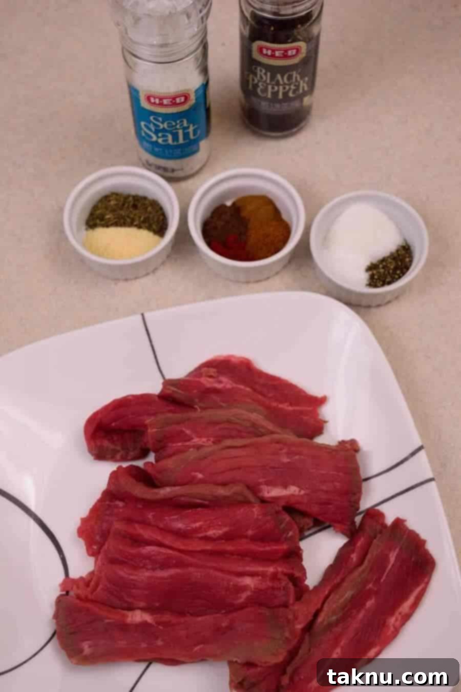 Close-up of a bowl of various Jamaican Jerk Beef Jerky spices, including vibrant red cayenne, dried thyme, and dark allspice