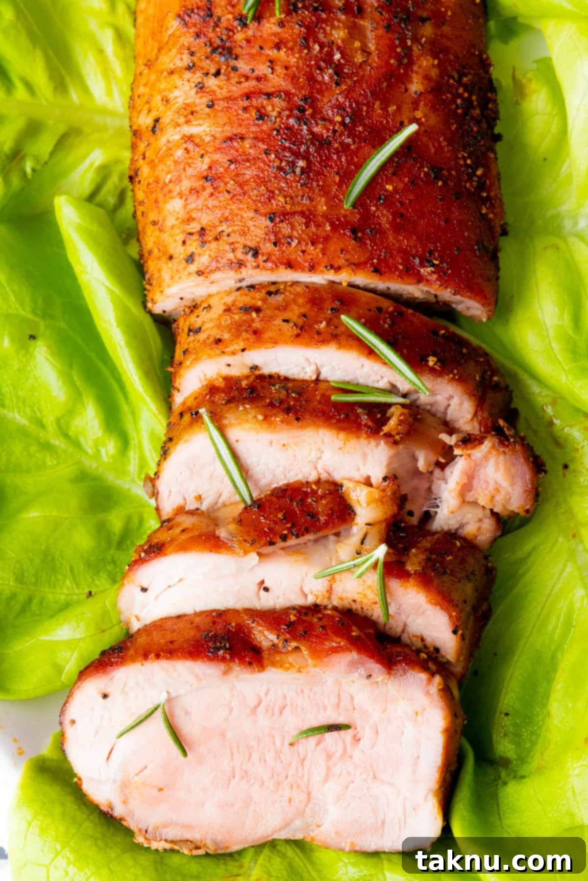 Perfectly Smoked Pork Tenderloin on a bed of fresh lettuce with garnish, ready to serve
