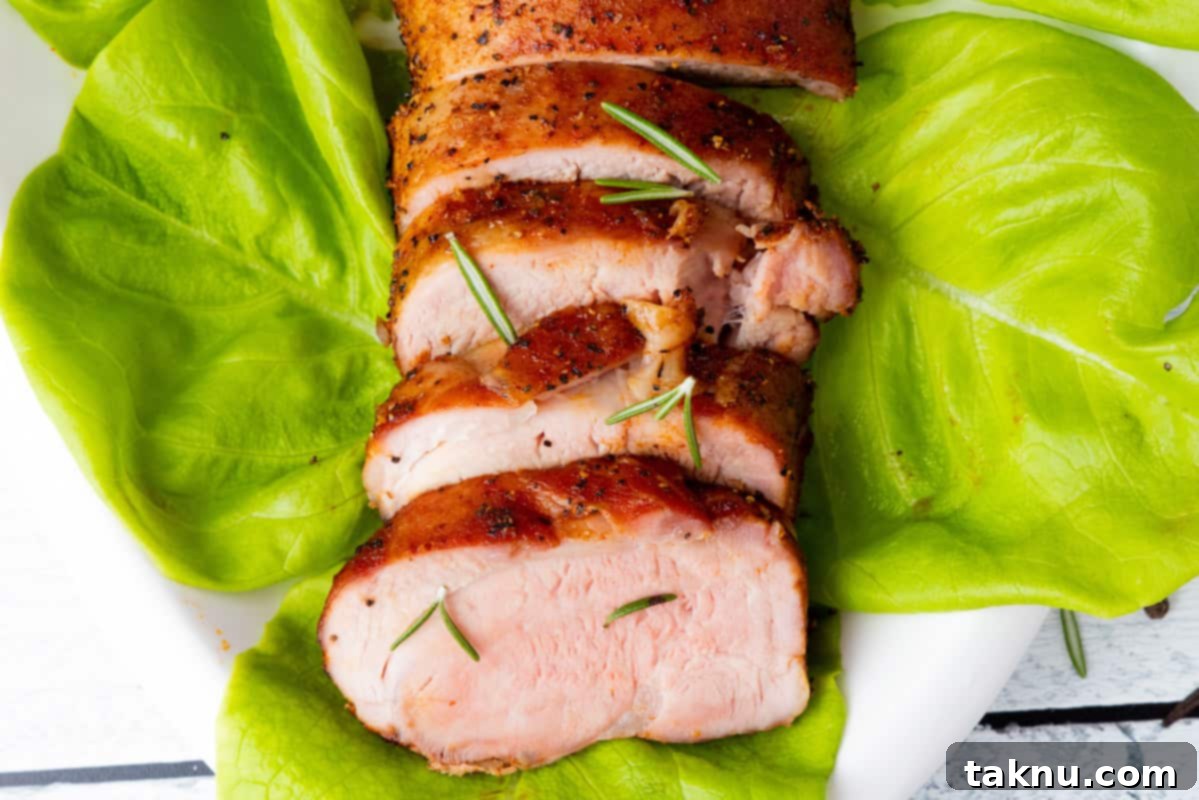 Sliced smoked pork tenderloin elegantly arranged on a bed of fresh lettuce with vibrant garnish, ready for serving.