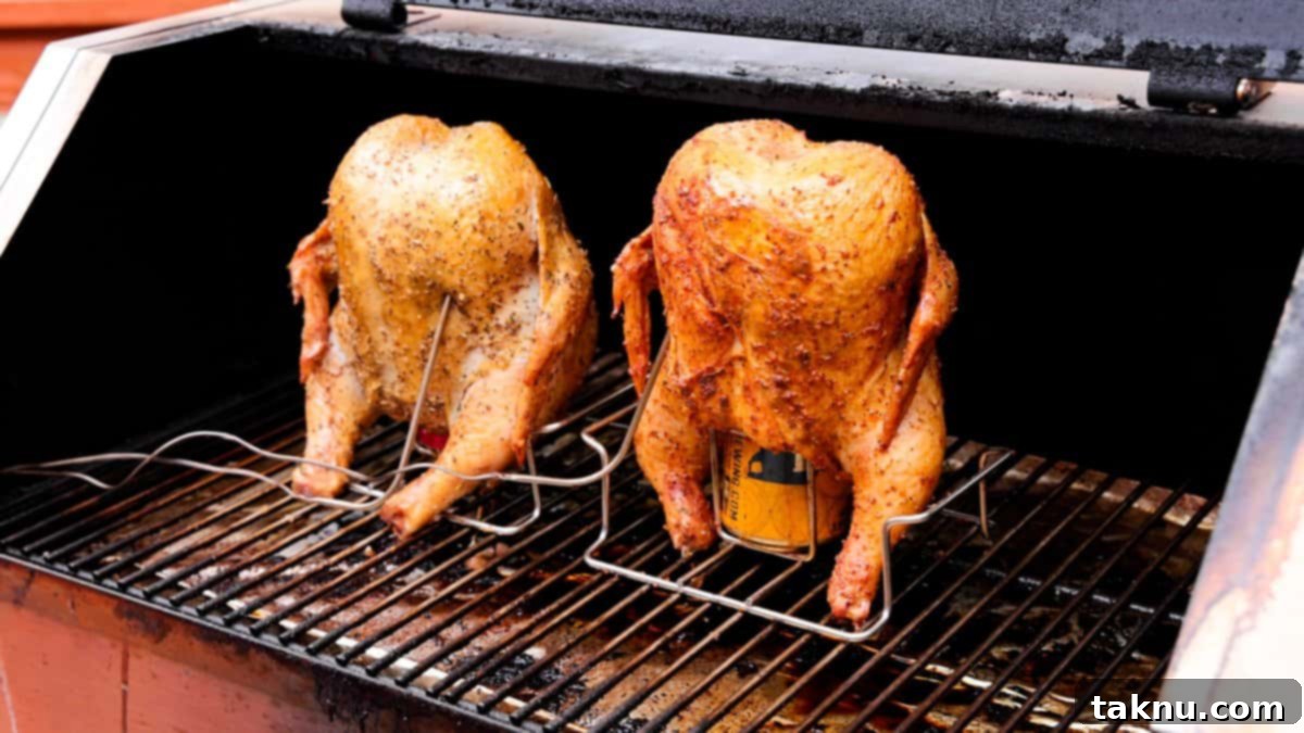 Ultimate Smoked Beer Can Chicken 7 Two chickens roasting upright on a grill with beer cans in their cavities, showcasing even smoke distribution and golden-brown skin.