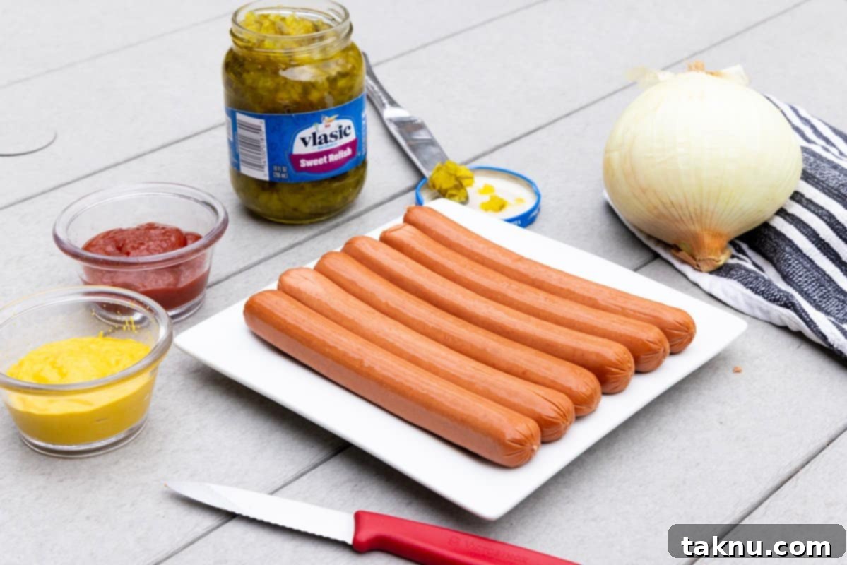 A selection of high-quality hot dogs arranged on a white plate, surrounded by classic condiments like mustard, ketchup, relish, and finely diced onions, ready for grilling or smoking.