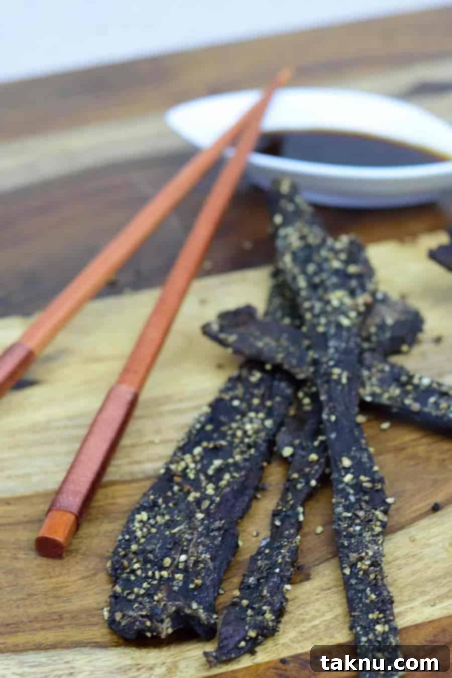 Finished Teriyaki Deer Jerky with sauce and chopsticks