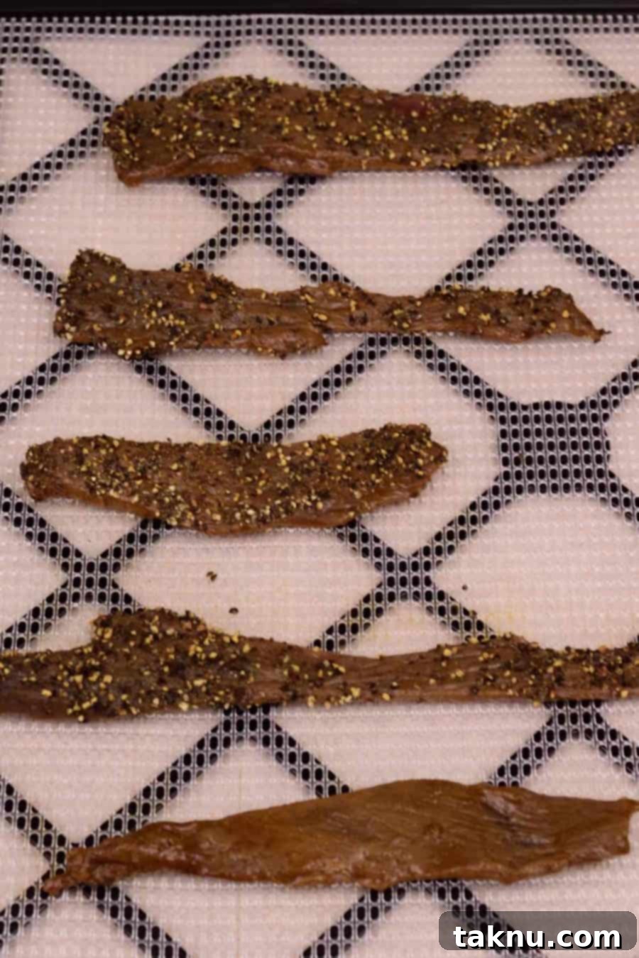 Deer jerky slices on dehydrator tray