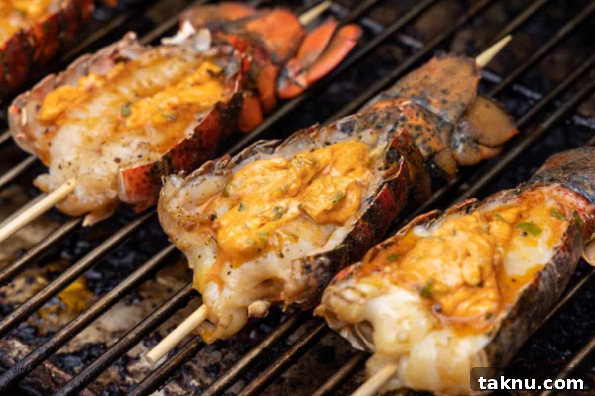 Lobster tails buttered on grill with wooden skewer stuck through tail.