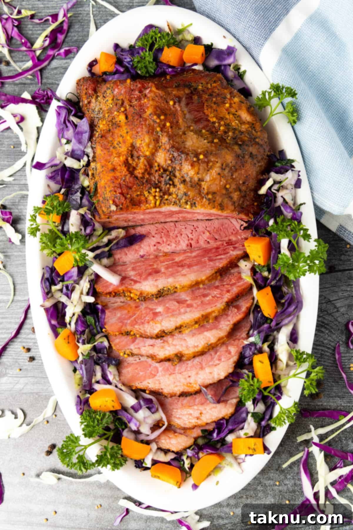 Slow-Smoked Corned Beef 2 Tender smoked corned beef slices on a white platter, accompanied by vibrant cabbage and carrots, ready to be served.